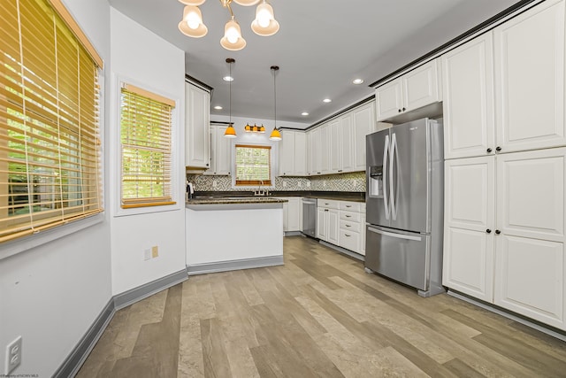 kitchen with white cabinets, backsplash, hanging light fixtures, and appliances with stainless steel finishes