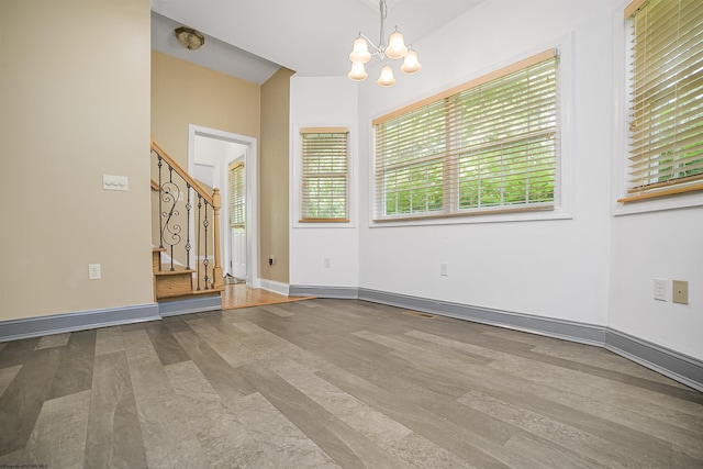 unfurnished room with hardwood / wood-style floors and a notable chandelier