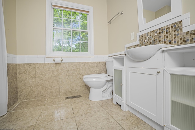 bathroom featuring tile patterned floors, vanity, toilet, and tile walls