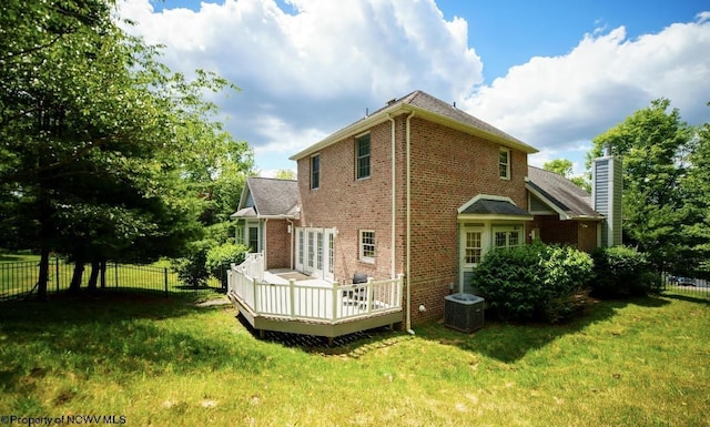 rear view of property featuring a deck, cooling unit, and a lawn