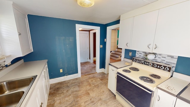 kitchen featuring electric range, decorative backsplash, white cabinets, and sink