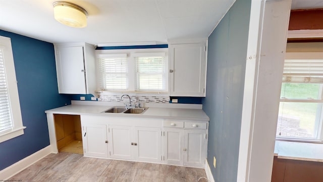 kitchen featuring decorative backsplash, white cabinetry, and sink