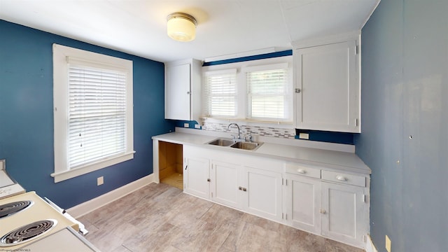 kitchen featuring plenty of natural light, decorative backsplash, white cabinetry, and sink