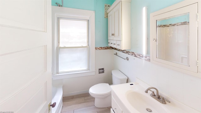 bathroom featuring a bathtub, vanity, wood-type flooring, and toilet