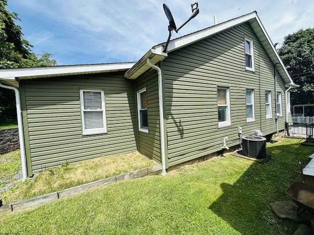 view of side of home featuring central AC and a yard