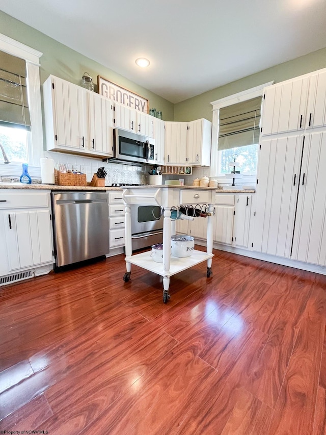 kitchen featuring decorative backsplash, a healthy amount of sunlight, white cabinetry, and stainless steel appliances