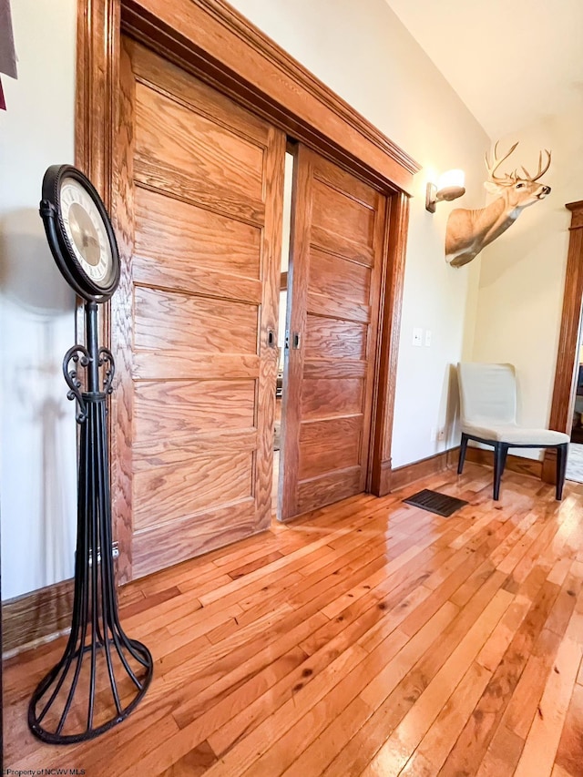 doorway with lofted ceiling and wood-type flooring