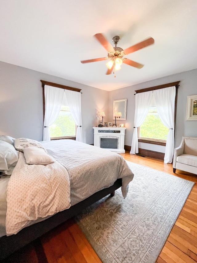 bedroom with ceiling fan, light wood-type flooring, and multiple windows