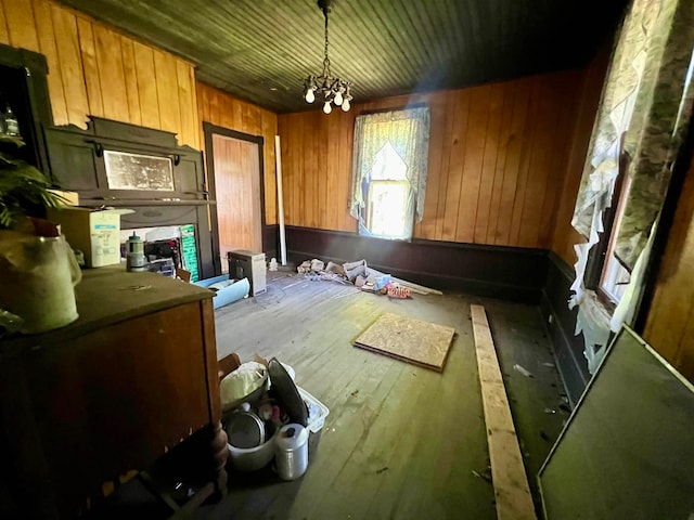 kitchen with decorative light fixtures, wood walls, a notable chandelier, and hardwood / wood-style floors