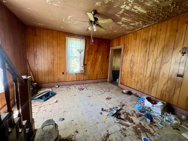 tiled empty room featuring wooden walls and ceiling fan