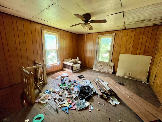 misc room featuring ceiling fan, wood walls, and hardwood / wood-style flooring