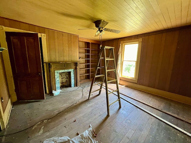 unfurnished living room featuring wood ceiling, wooden walls, wood-type flooring, and ceiling fan