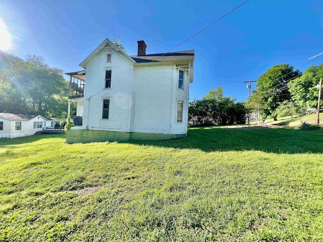 view of side of property with a balcony and a yard