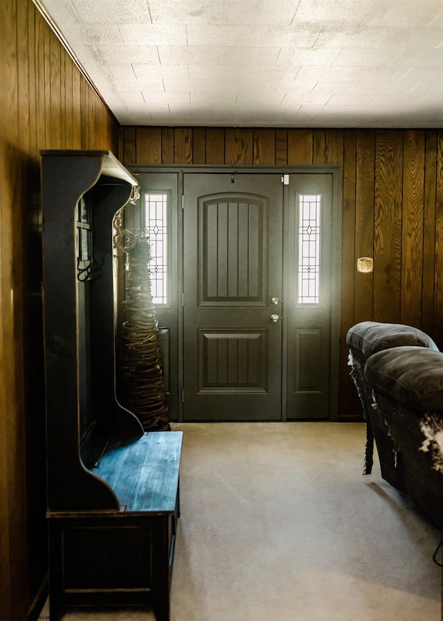 foyer featuring light colored carpet and wooden walls