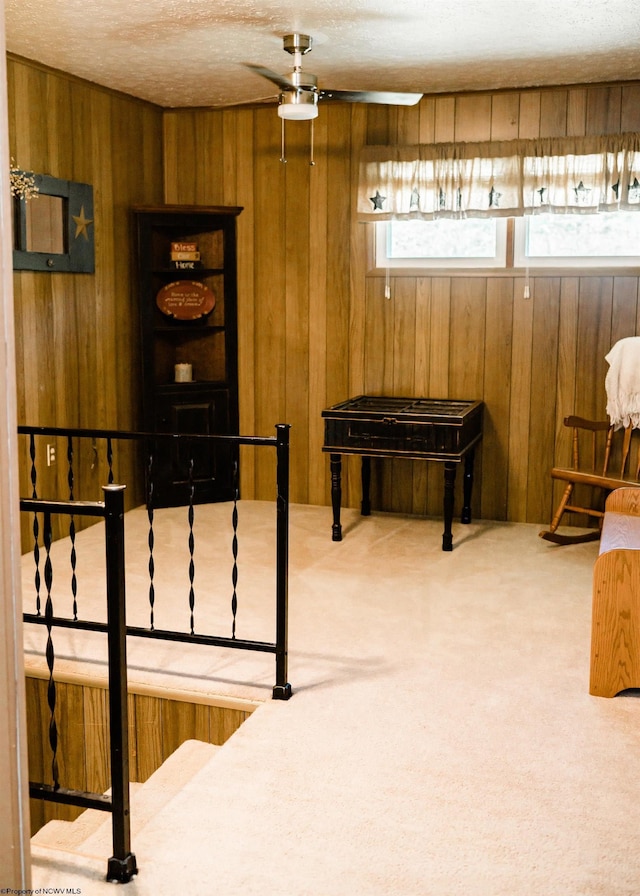 game room featuring a textured ceiling, carpet floors, and wood walls