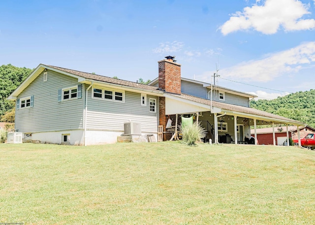 rear view of property featuring a lawn and central air condition unit