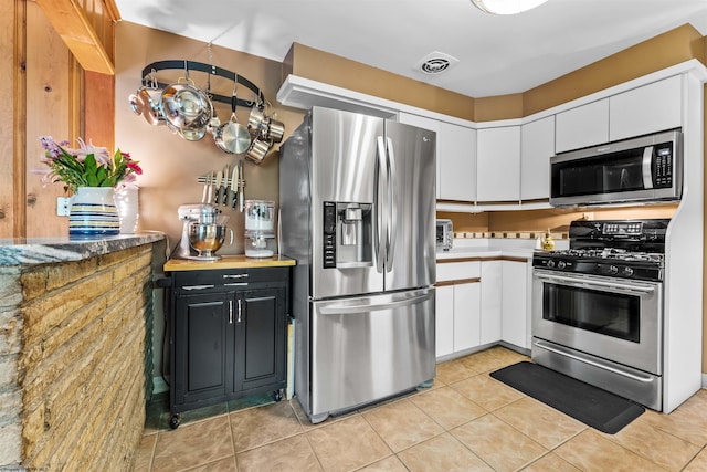 kitchen with white cabinets, light tile patterned floors, and appliances with stainless steel finishes