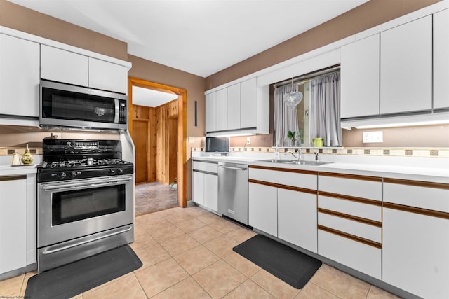 kitchen with white cabinets, sink, light tile patterned floors, and stainless steel appliances