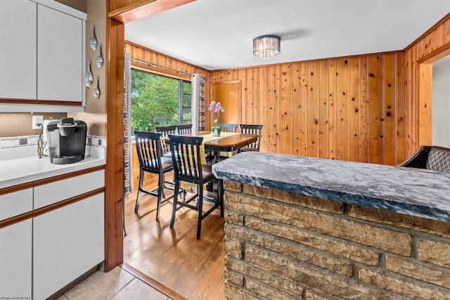 dining space featuring light wood-type flooring, crown molding, and wood walls