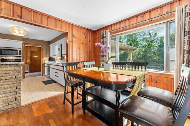 dining room featuring light wood-type flooring, crown molding, wooden walls, and sink