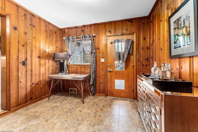 entrance foyer featuring crown molding and wooden walls