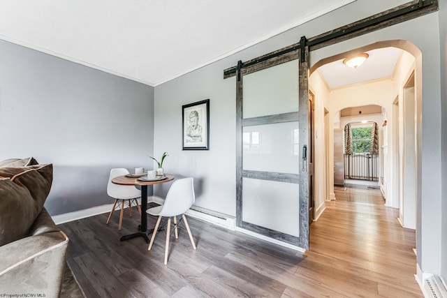 dining space featuring crown molding, a barn door, and hardwood / wood-style flooring