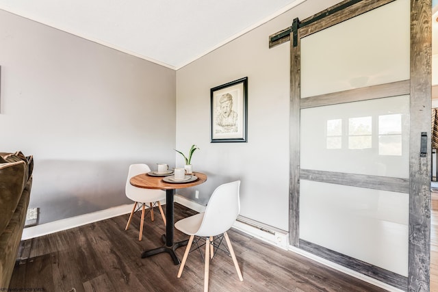 dining room with hardwood / wood-style flooring, ornamental molding, and a barn door