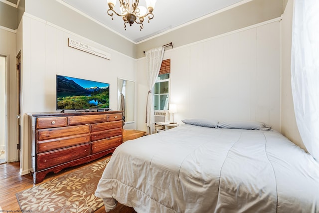 bedroom featuring ornamental molding, wood-type flooring, and a chandelier