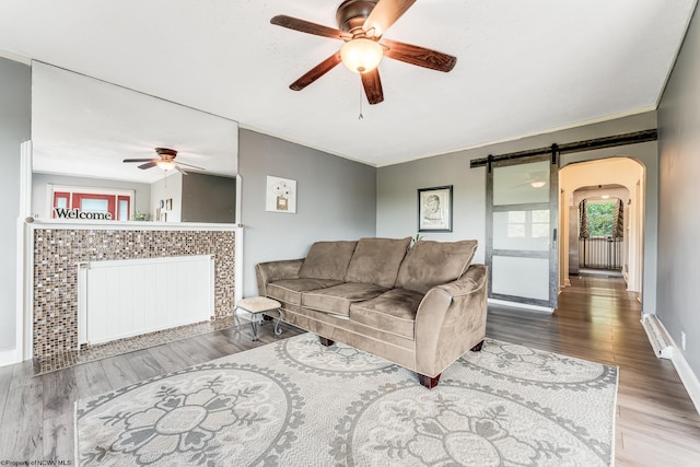 living room featuring radiator, hardwood / wood-style floors, a barn door, and ceiling fan