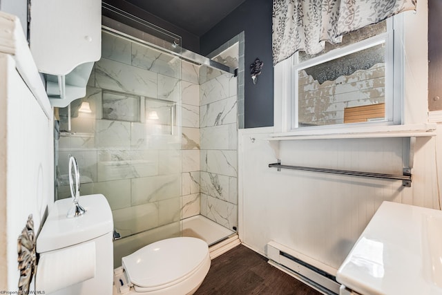 bathroom featuring hardwood / wood-style flooring, a baseboard heating unit, a tile shower, and toilet