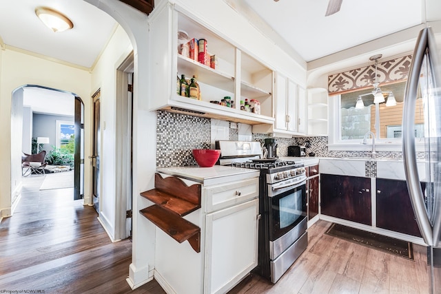 kitchen featuring white cabinetry, tasteful backsplash, gas stove, and hanging light fixtures