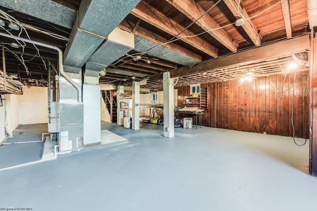 basement with heating unit and wooden walls