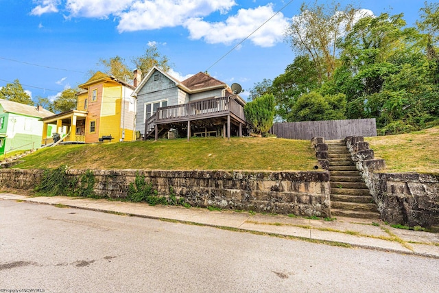 view of front of house with a wooden deck and a front lawn