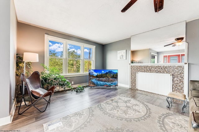 living area featuring ceiling fan, radiator heating unit, hardwood / wood-style floors, and ornamental molding