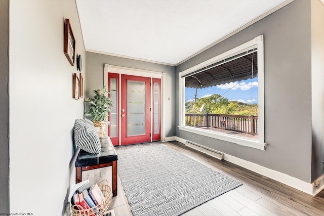 entrance foyer featuring hardwood / wood-style flooring, ornamental molding, and a baseboard heating unit