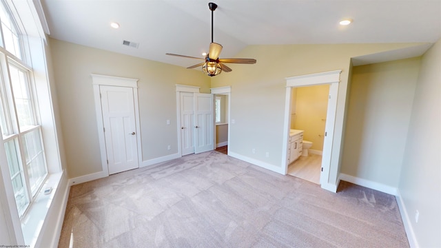 unfurnished bedroom featuring ceiling fan, multiple windows, light carpet, and vaulted ceiling