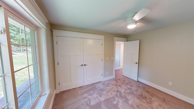 unfurnished bedroom featuring ceiling fan, light carpet, and a closet