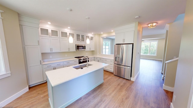 kitchen with sink, decorative light fixtures, a center island with sink, white cabinets, and appliances with stainless steel finishes