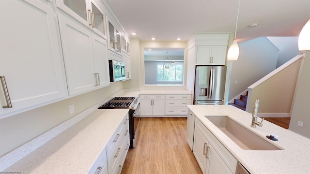 kitchen featuring white cabinets, appliances with stainless steel finishes, light stone countertops, and pendant lighting