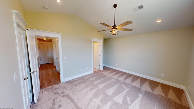 unfurnished bedroom featuring ceiling fan, light carpet, and vaulted ceiling