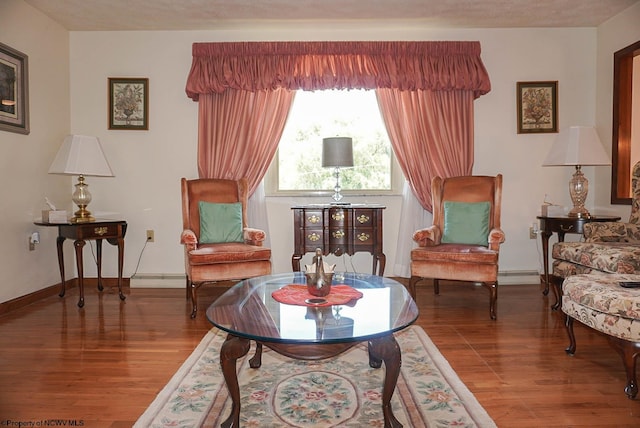 living area featuring baseboard heating and hardwood / wood-style floors