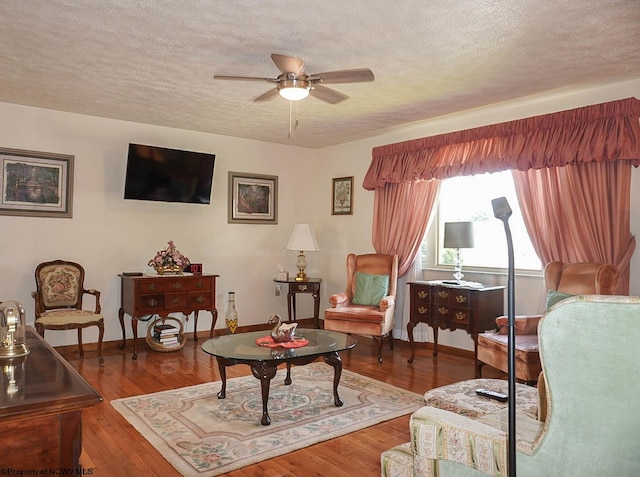 living room featuring ceiling fan, hardwood / wood-style flooring, and a textured ceiling