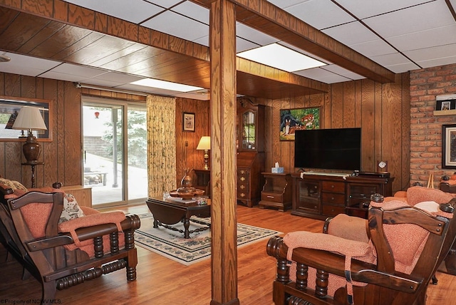 living room featuring wood walls, hardwood / wood-style flooring, and brick wall