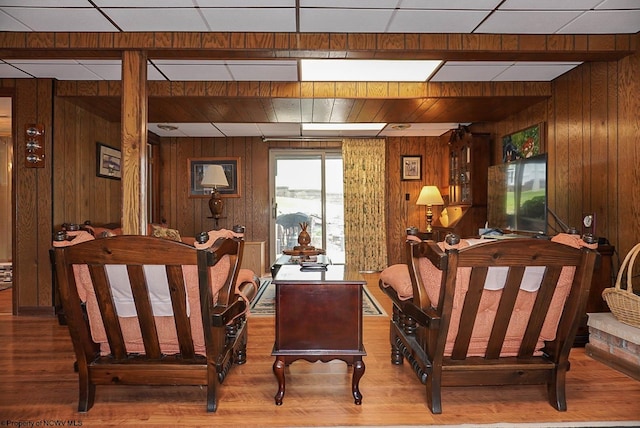 living room featuring wood walls, hardwood / wood-style flooring, and a drop ceiling