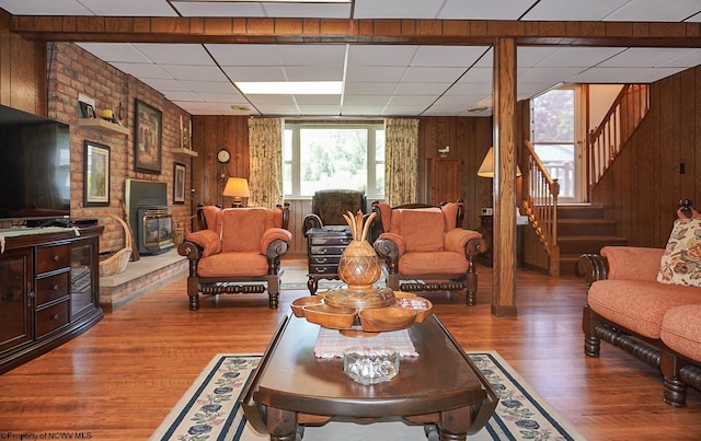 living room with wood walls, a paneled ceiling, dark hardwood / wood-style flooring, and a fireplace