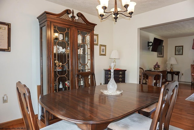 dining area with a chandelier, hardwood / wood-style flooring, and a textured ceiling