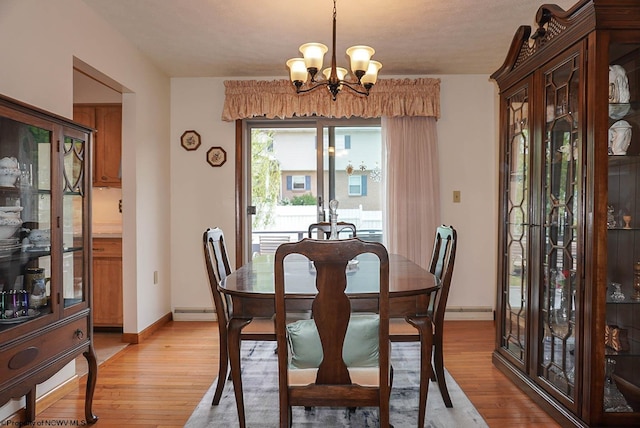 dining room featuring a notable chandelier, baseboard heating, and light hardwood / wood-style floors