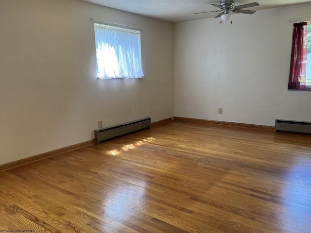 empty room featuring hardwood / wood-style flooring, ceiling fan, and baseboard heating