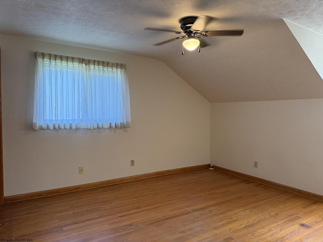 additional living space featuring hardwood / wood-style floors, ceiling fan, a textured ceiling, and vaulted ceiling