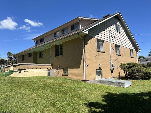 rear view of property with central air condition unit and a lawn